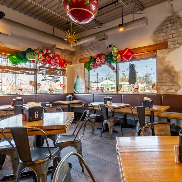 Interior of Taquerias Atotonilco restaurant decorated for Christmas with tables, chairs, and window views.