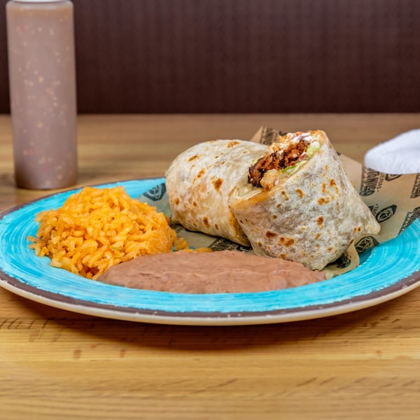A Taquerias Atotonilco burrito, rice, and refried beans on a blue plate with a sauce bottle.