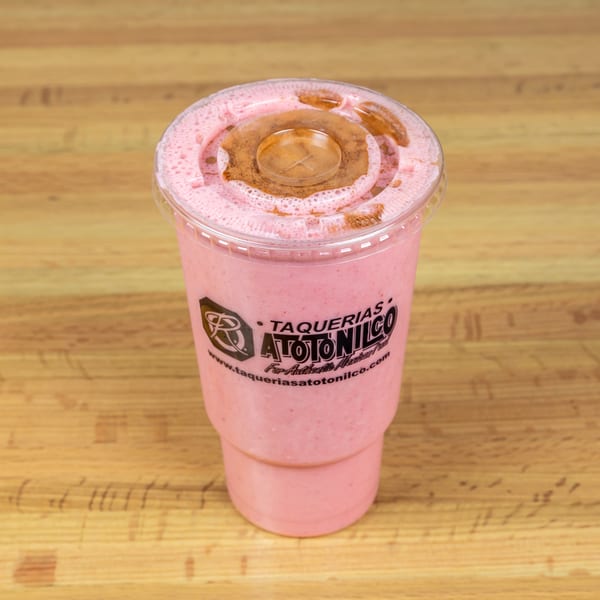 Pink strawberry horchata with cinnamon powder and a clear lid, from Taquerias Atotonilco.