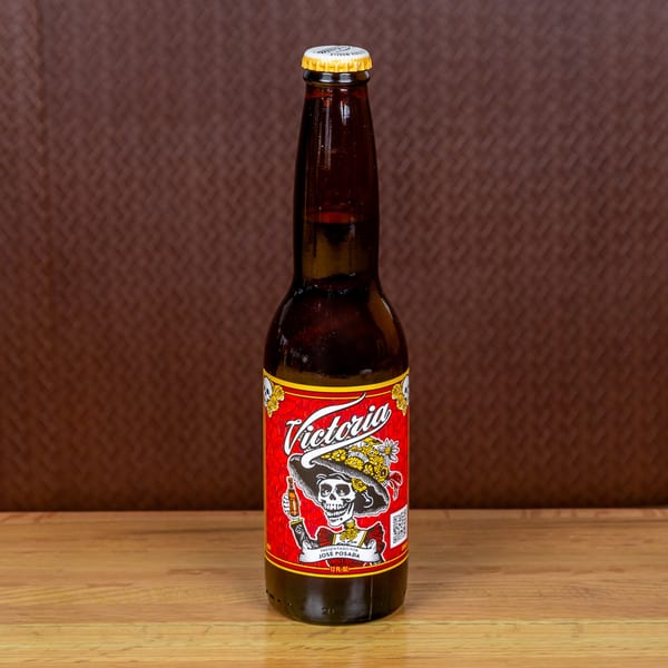 A bottle of Victoria beer with a red label featuring a skeleton in a sombrero.