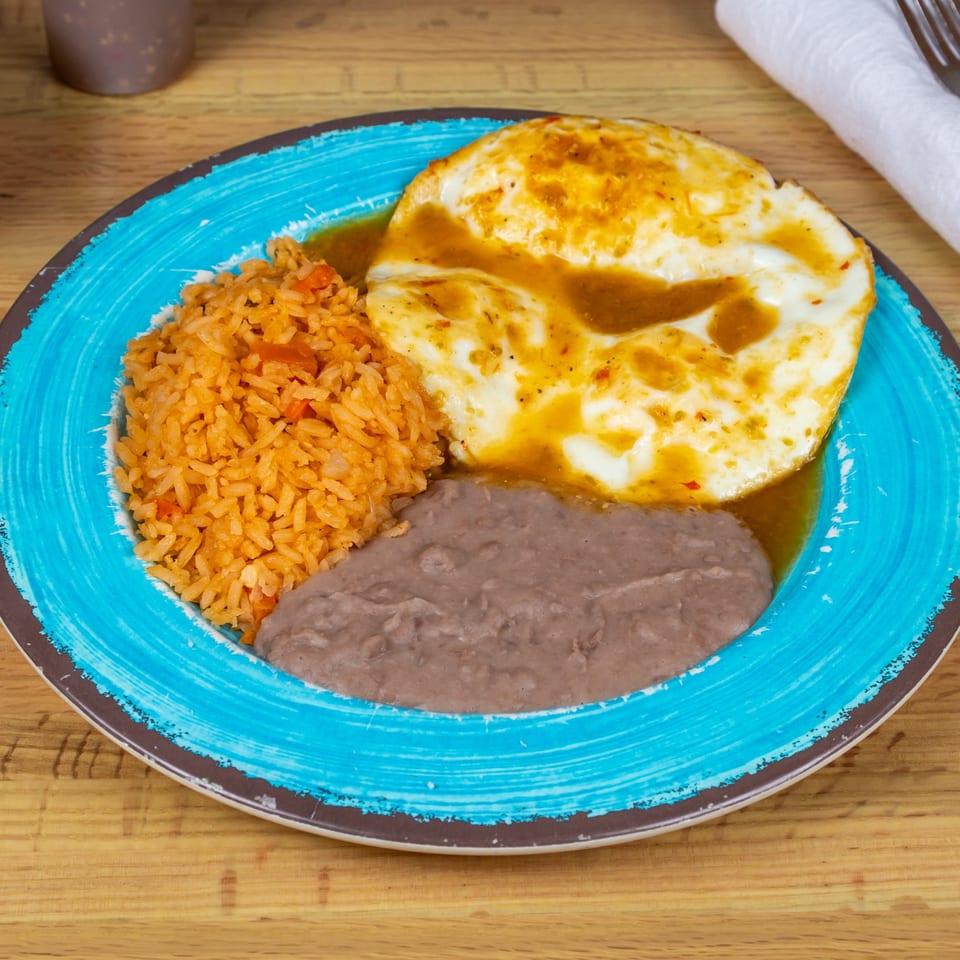 Huevos rancheros with rice and refried beans on a blue and brown plate.